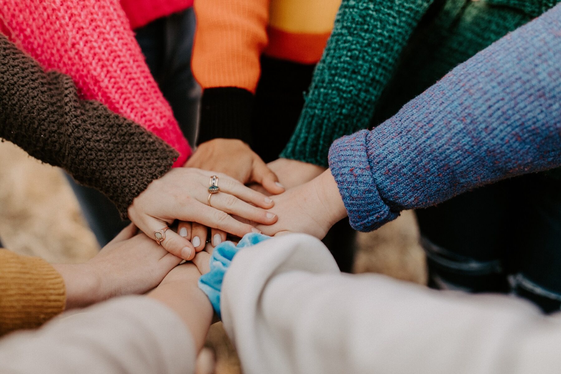 people standing in a circle with their hands together in the middle